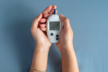 Woman's hands checking diabetes and hyperglycemia with digital blood sugar meter. Healthcare and medical concept	