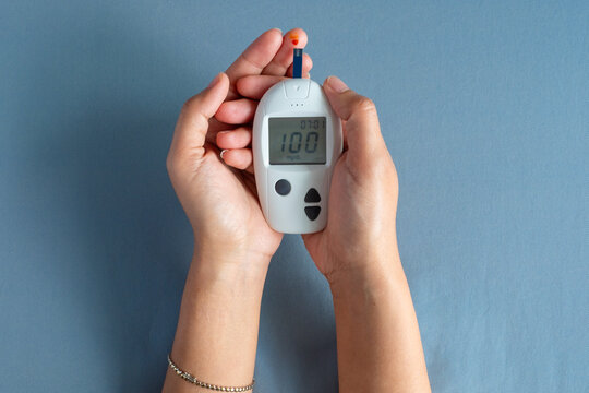 Woman's hands checking diabetes and hyperglycemia with digital blood sugar meter. Healthcare and medical concept	