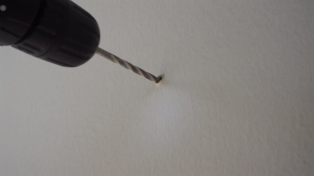 Close-up of cordless drill making a hole in wall for home DIY project.