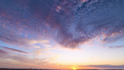 Vibrant purple sunset sky above horizon showing sweeping cirrus clouds, soft pink and gold light, low sunflare and expansive panorama evoking calm and wonder during golden hour