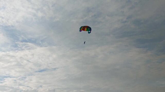 person doing adventure parasailing in sky with clouds. day time, slight pan shot, 4k.