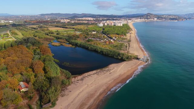 Aerial drone footage of the tordera river delta, where the freshwater lagoon meets the mediterranean sea in a unique natural landscape on the coast of blanes, catalonia, spain