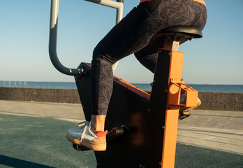 Exercising on outdoor bike equipment by the sea during morning light