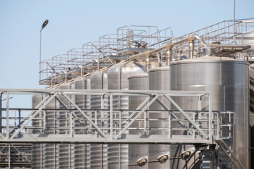 Large metal storage tanks in an industrial facility under a clear blue sky during daytime