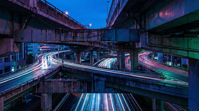A vibrant view of a complex urban overpass at dusk, showcasing light trails from vehicles against a blue sky. Ideal for urban travel themes.