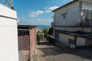 快晴の空とエメラルドグリーンの海の見える街並みと下り坂