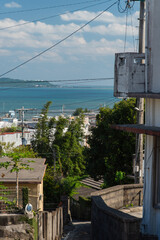 快晴の空とエメラルドグリーンの海の見える街並みと下り坂