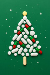 Creative Christmas tree made of colorful pills on green background