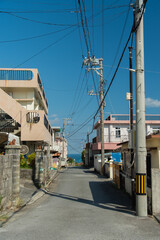 奥にエメラルドグリーンの海の見える天気の良い町の路地裏の直線道