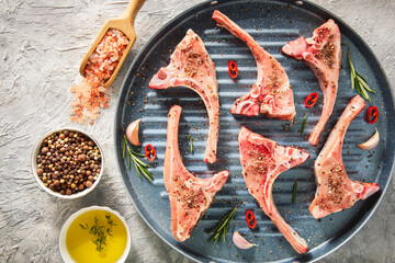 Fresh raw lamb meat chops with spices and herbs, ready for grilling. Top view with close up.