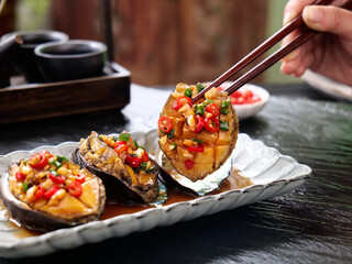 Grilled Abalone Seafood with Garlic and Chili Being Eaten with Chopsticks at Asian Restaurant