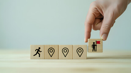 Hand placing a wooden block with a person and flag next to blocks with location markers and a running person
