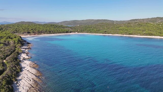 Drone flight over Sakarun Beach bay on Dugi Otok, Croatia. Returning across lush islands and vivid turquoise waters, revealing a natural wild bay with stunning coastal scenery.