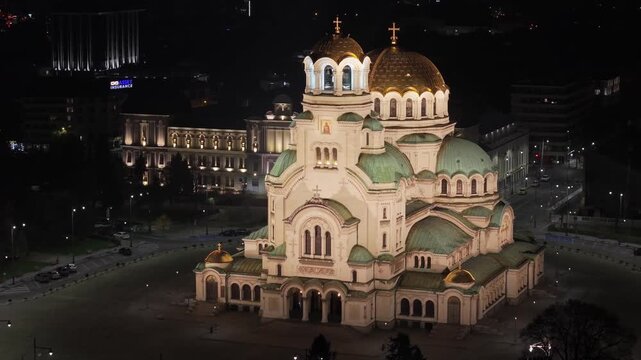 A drone orbit captures the majestic illuminated Alexander Nevsky Cathedral glowing against the night sky, revealing its golden domes and dominating presence in Sofia&rsquo;s city center.