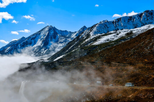Winding Road Across Snowcapped Mountain Peaks Under Brilliant Blue Sky