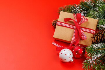 Gift box on snowy fir branches and red background