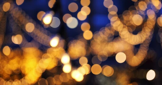 Blurry, defocused, bokeh balls effect of hanging string lights at night. Panning shot, real time, no people