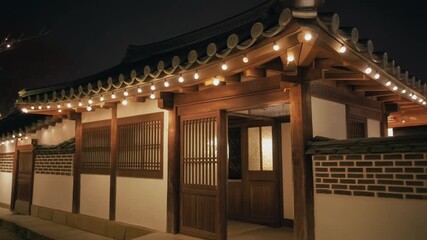 Peaceful night scene of a traditional Korean Hanok house, its classic tiled roof elegantly illuminated by a string of warm lights