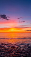 Obraz premium Vibrant sunset over the ocean, with colorful sky and water reflections.