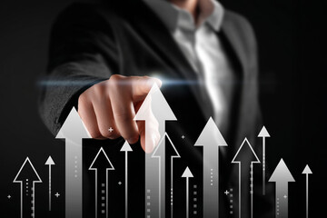 Businessman hand pointing at digital glowing arrows rising up. Concept of business growth, financial success, stock market upward trend, and progress.