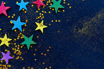 Colorful glitter stars on dark blue background with copy space for text