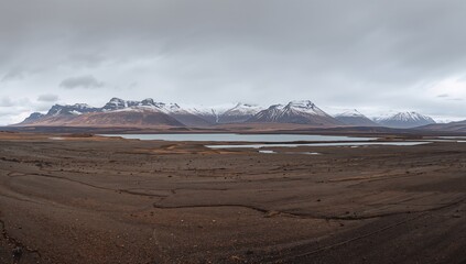 Wide landscape of Iceland's autumn highlands featuring lava fields and distant snow-capped volcanic mountains, seasonal change