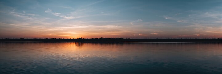 Sunset over a calm lake with a silhouetted pier reflecting pastel hues, ideal for relaxation and meditation, Earth Day