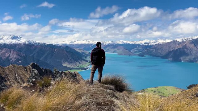Hiker on Isthmus peak views Lake Hawea and vast mountains in Otago, New Zealand, feeling serene