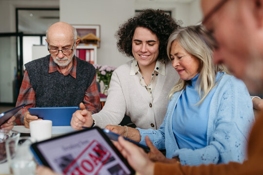 Volunteer teaching seniors how to recognize fake news on digital tablet.