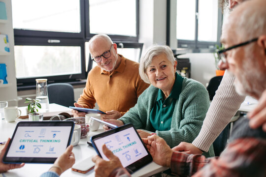 Group of senior people learning digital skills with tutor help.