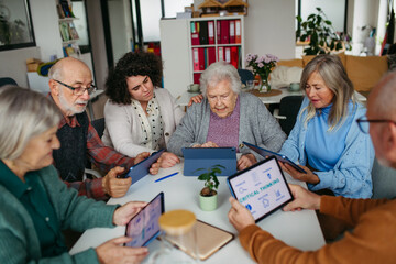 Group of senior people learning digital skills with tutor help.