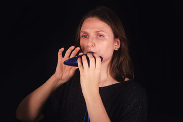 Woman playing blue ocarina musical instrument. Female musician performing traditional wind music. Expressive melody and concert concept.