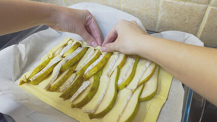 Making pear pastry, pie on a baking sheet in the kitchen