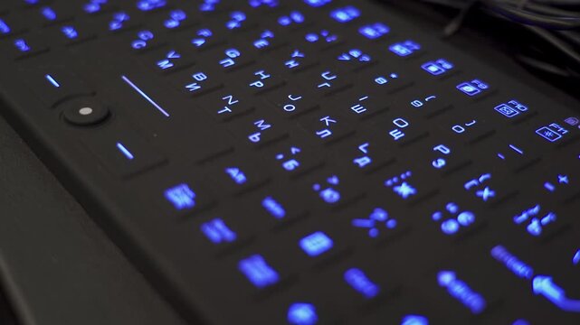 Close-up sliding camera move over blue backlit keyboard. Soft motion reveals glowing keycaps and a modern tech atmosphere