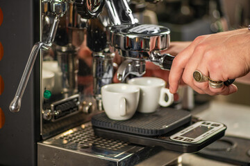 Barista operating espresso machine in modern cafe. Close-up shot showing steam, crema, and precision of professional coffee preparation.