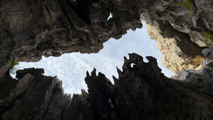 A view of the blue sky from a deep pit with sharp rocks