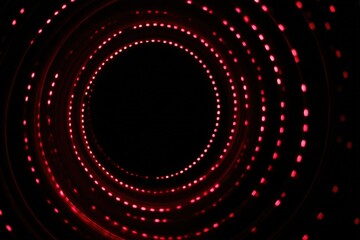 Circular red light pattern in dark tunnel with glowing dots