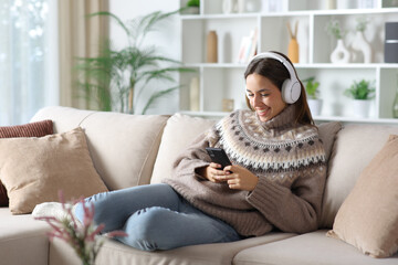 Happy woman in winter watching online media on smart phone