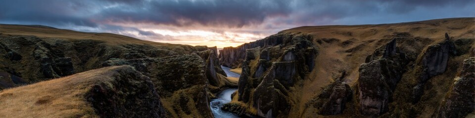 Obraz premium Majestic canyon at sunset with river and dramatic sky in iceland