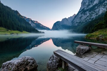 Tranquil mountain lake at dawn with mist and reflective water surface