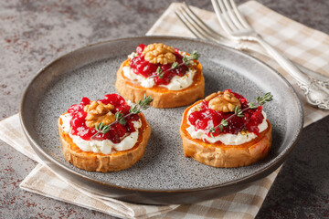 Healthy holiday food sweet potato with cream cheese, cranberry sauce, thyme and walnuts close-up in a plate on the table. Horizontal
