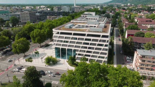 Orbiting drone shot around the European Patent Office with park, streets and modern district.