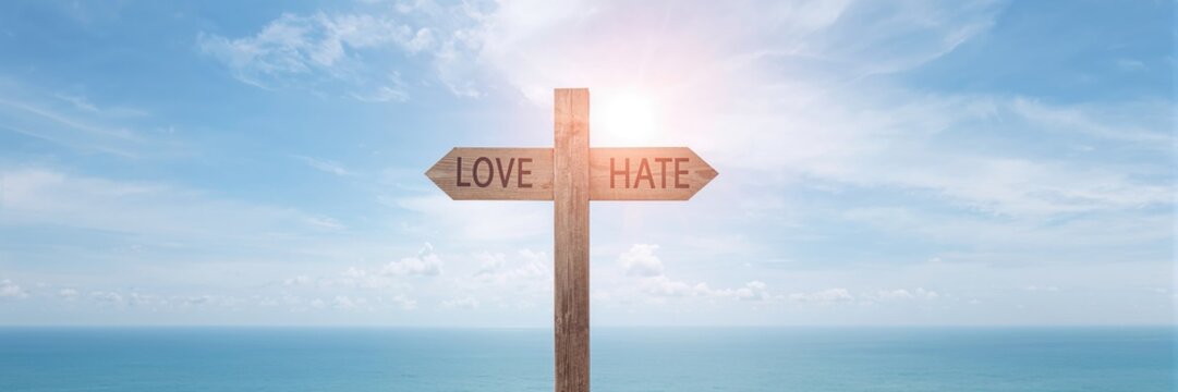Pile of handmade sweaters on a gray sofa with cozy blanket and decorative lights in a living room setting, emphasizing comfort and home decor