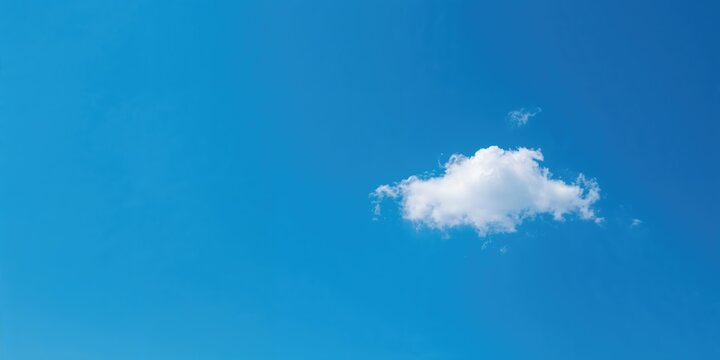 Single cloud in a vast blue sky as a background for text layout, emphasizing simplicity and open space