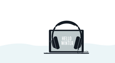 Modern laptop with headphones displaying hello winter text on screen for seasonal greetings