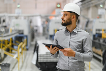 Industrial engineer holding tablet and supervising production line in factory