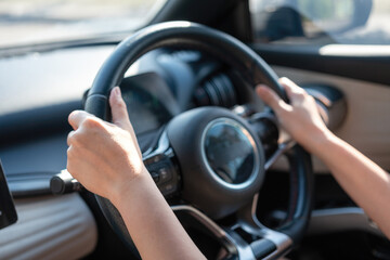 Naklejka premium Action of a driver is gripping on steering wheel to control the car during driving. Transportation mode with close-up and selective focus on the hand.