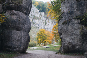 Dramatic rock formations frame a scenic view of autumn foliage and cliffs