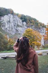 Woman in a brown coat admiring the autumn scenery of a rocky mountain