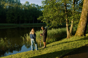 Couple enjoys fishing together at a serene pond surrounded by trees